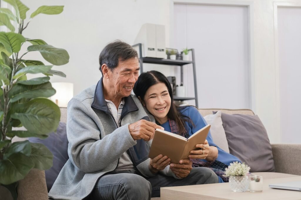 Elderly Couple Relaxing in Cozy Living Room, Reading Book Together, Enjoying Quality Time