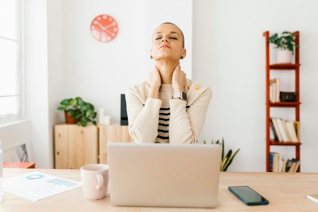 Mid adult woman suffering from neck pain in home office