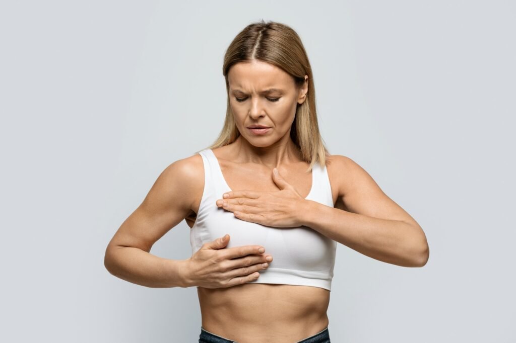 Anxious middle aged blonde woman examining her breasts